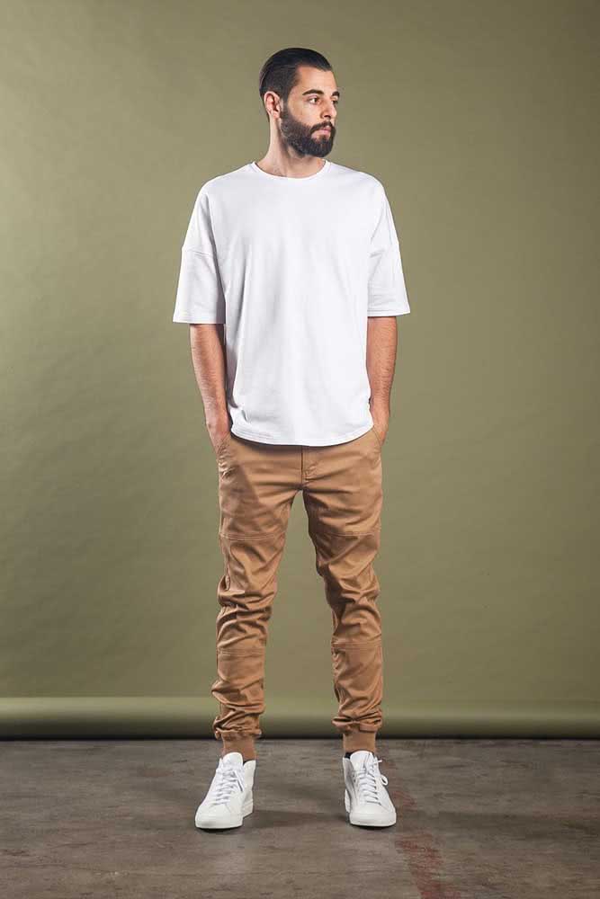 Simples, mas não sem personalidade, um visual com calça jogger masculina cáqui, camiseta e tênis branco.