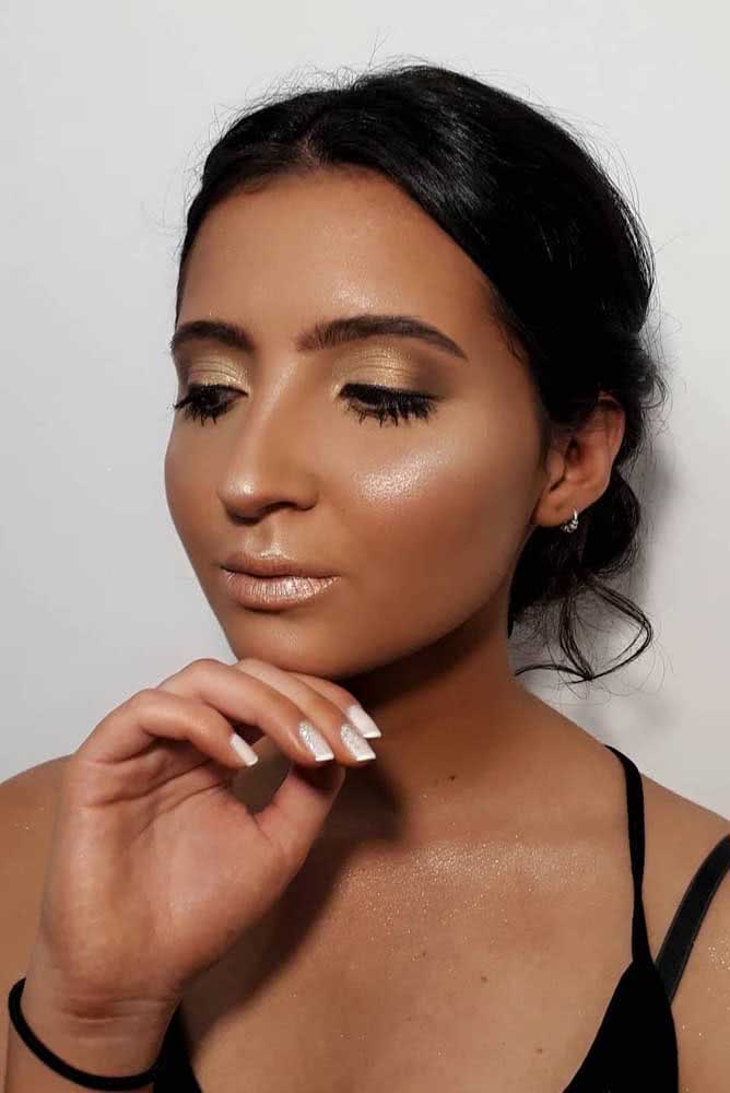 Quer uma make natural cheia de brilho e iluminação? Confira este visual com sombra dourada clarinha esfumada, cílios com máscara preta, um toque de iluminação no blush e batom nude com acabamento cintilante.