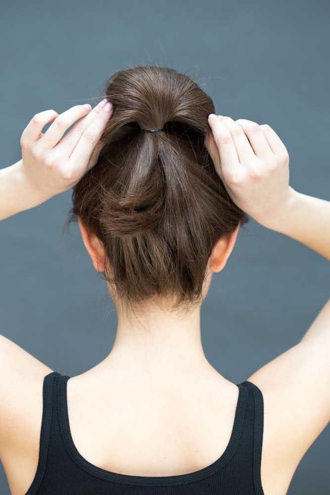 Prenda o cabelo com um elástico na altura desejada da cabeça e deixe o comprimento do cabelo dobrado para fazer um coque simples e despojado em poucos segundos.