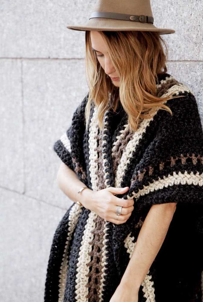 Poncho de crochê aberto e em padrão listrado em preto, marrom e branco, perfeito para curtir um festival de inverno em look boho.
