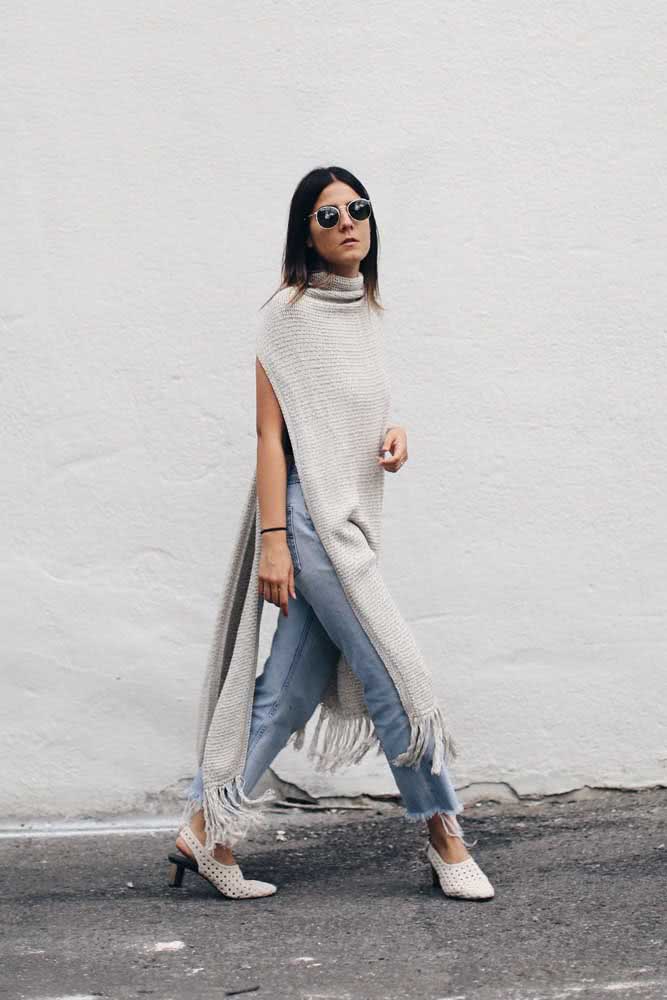 Muito movimento e elegância neste look com poncho de crochê retangular cinza bem alongado e com franjas nas barras. 