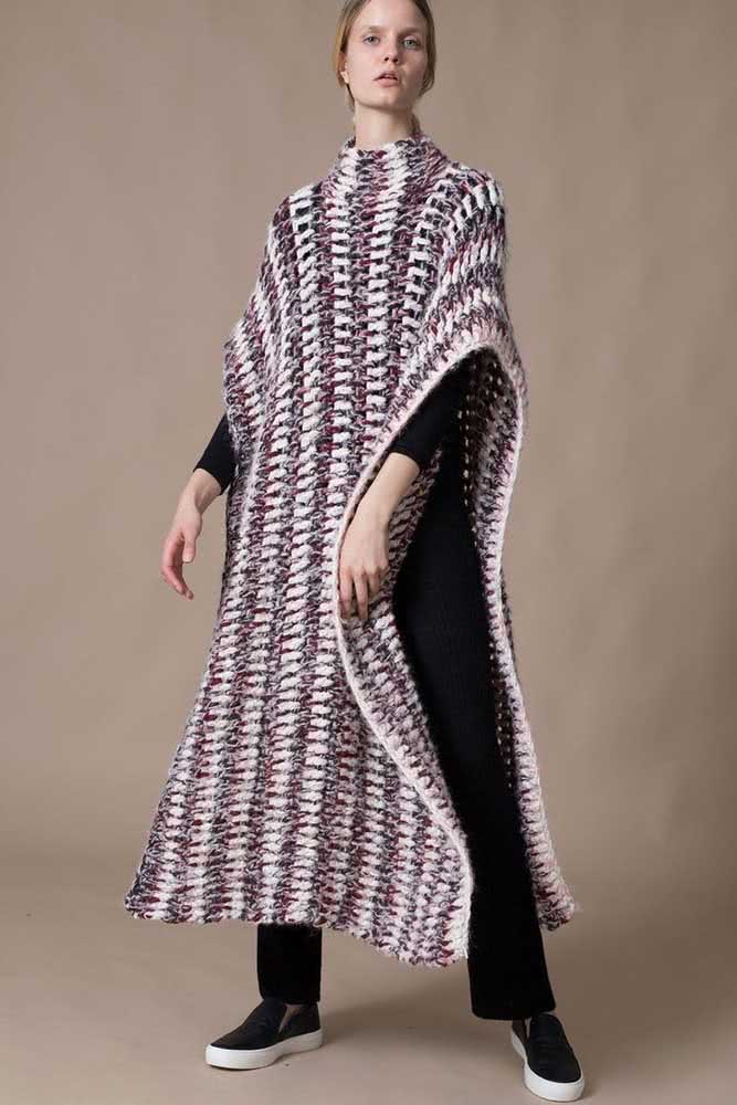 Com muito movimento e atitude, um poncho de crochê bem alongado feito com linha mesclada em listras verticais.