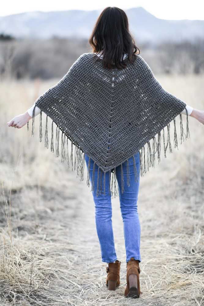 O poncho de crochê triangular com franja na barra é sempre uma escolha certa para qualquer look casual.