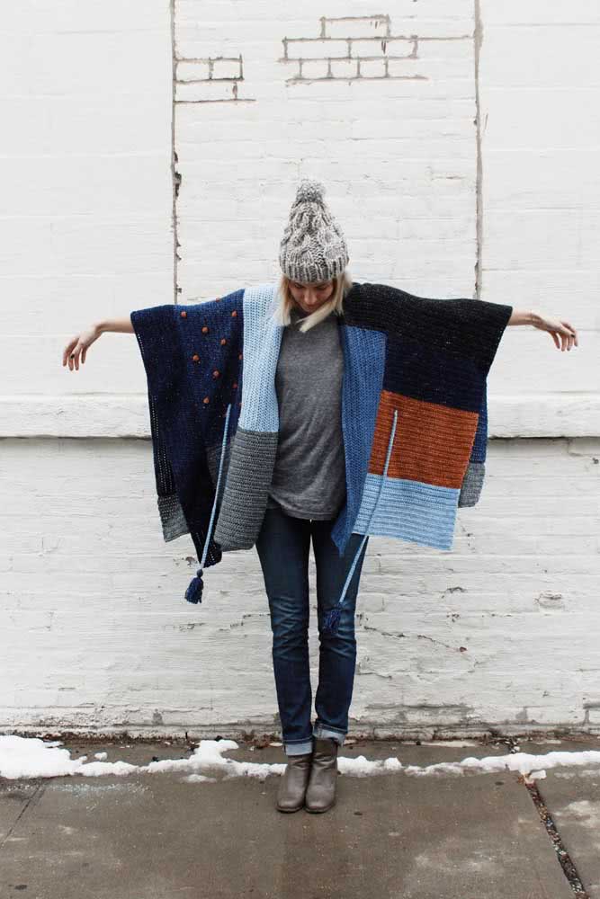Um poncho de crochê retangular dividido em tons frios é a escolha perfeita para compor um look casual e permanecer quentinha. 