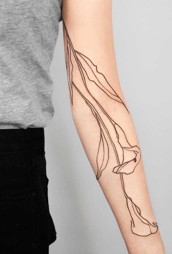 Outra ideia de tatuagem grande, que se estende pelo braço e antebraço com motivo floral: dessa vez representando dois lírios em um traço fino e livre. 