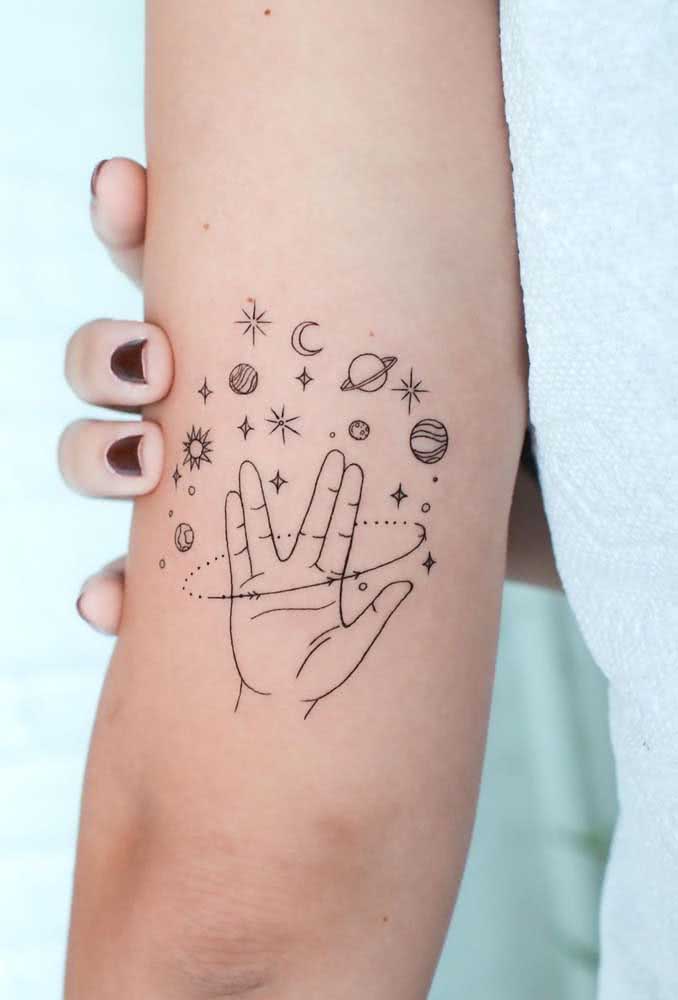 Para quem adora astronomia e cultura pop, uma tatuagem com diferentes planetas e estrelas rodeando uma mão que faz o gesto de saudação dos vulcanianos, de Star Trek.