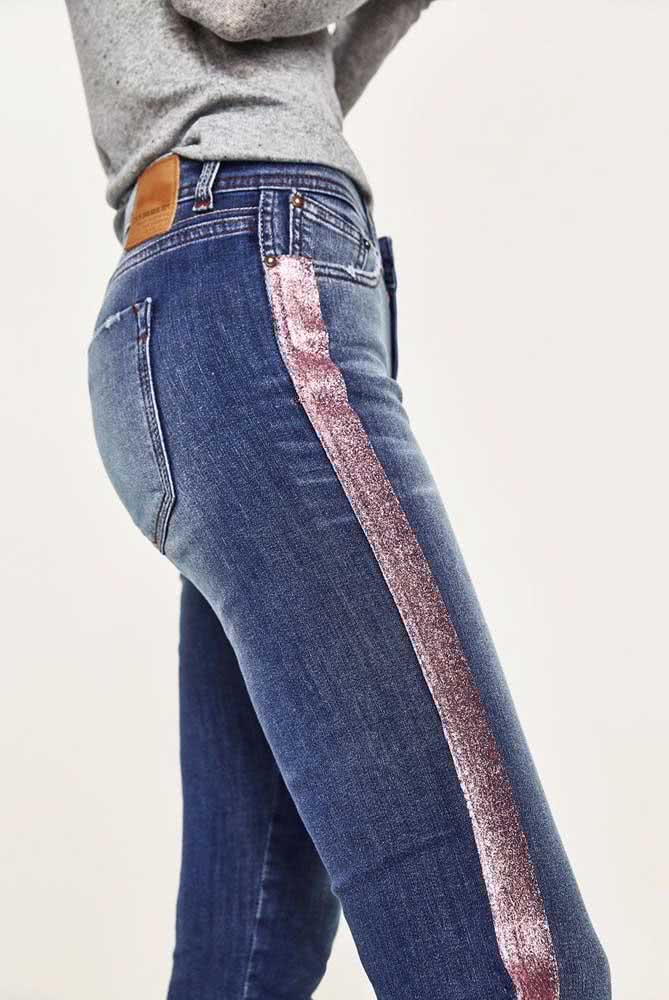 Uma faixa rosa claro com efeito perolado na lateral da perna tira o jeans azul do básico.