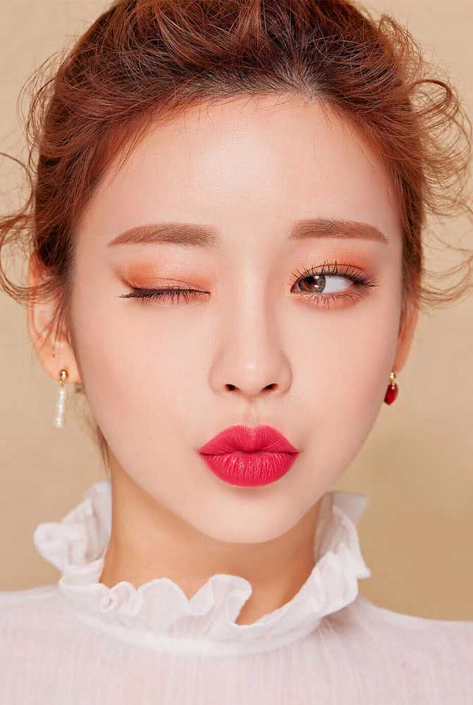 A combinação de cores quentes - como o vermelho e dourado - é perfeita para criar uma maquiagem coreana, seja ela mais sutil ou cheia de atitude como esta aqui.