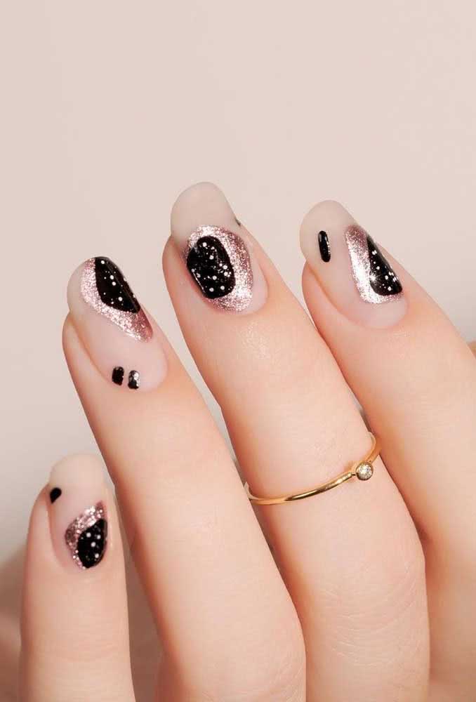 Uma composição linda e cheia de contrastes nesta unha decorada com fundo claro fosco e formas orgânicas em esmalte metalizado e preto com muito glitter!