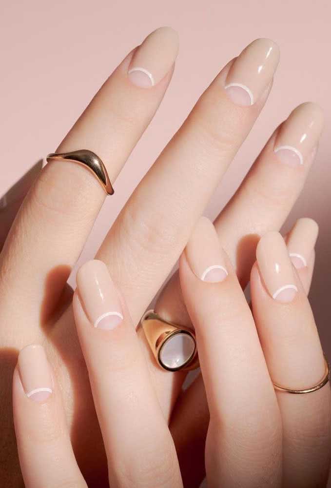 Simplicidade, elegância e tendência nestas nail arts nude com contorno branco na meia lua. 