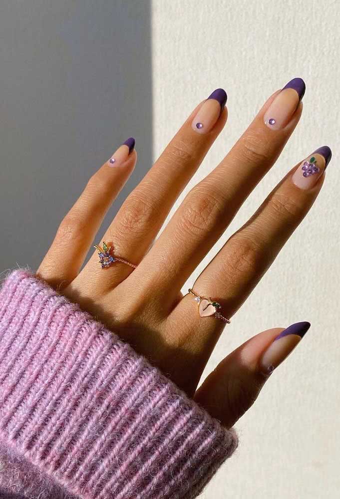 Num padrão divertido e jovial, unhas decoradas com pedra tipo strass em cada unha e fazendo um padrão de uva no indicador e francesinha roxa. 