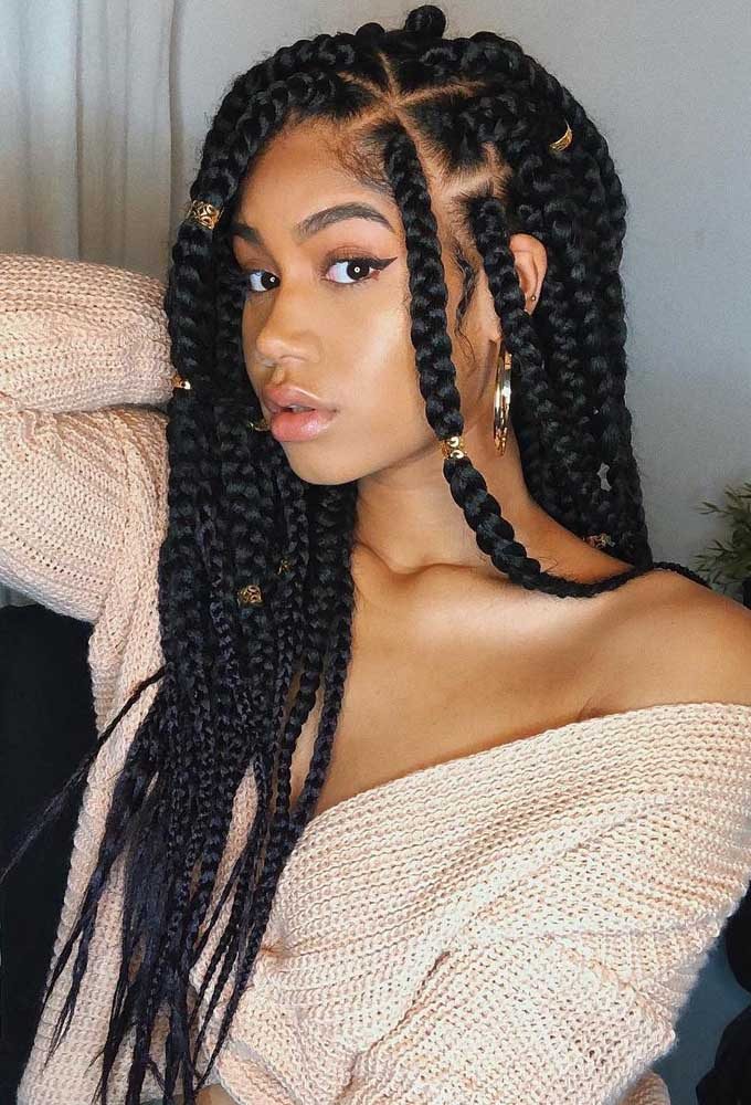 Box braids decoradas com anéis dourados, combinando com o brinco e colar escolhido para o look.