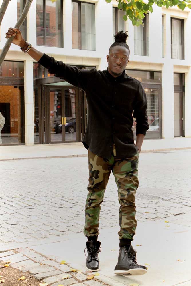 Neste look streetwear, a calça camuflada jogger se destaca entre a camisa e o tênis de cano médio pretos. 