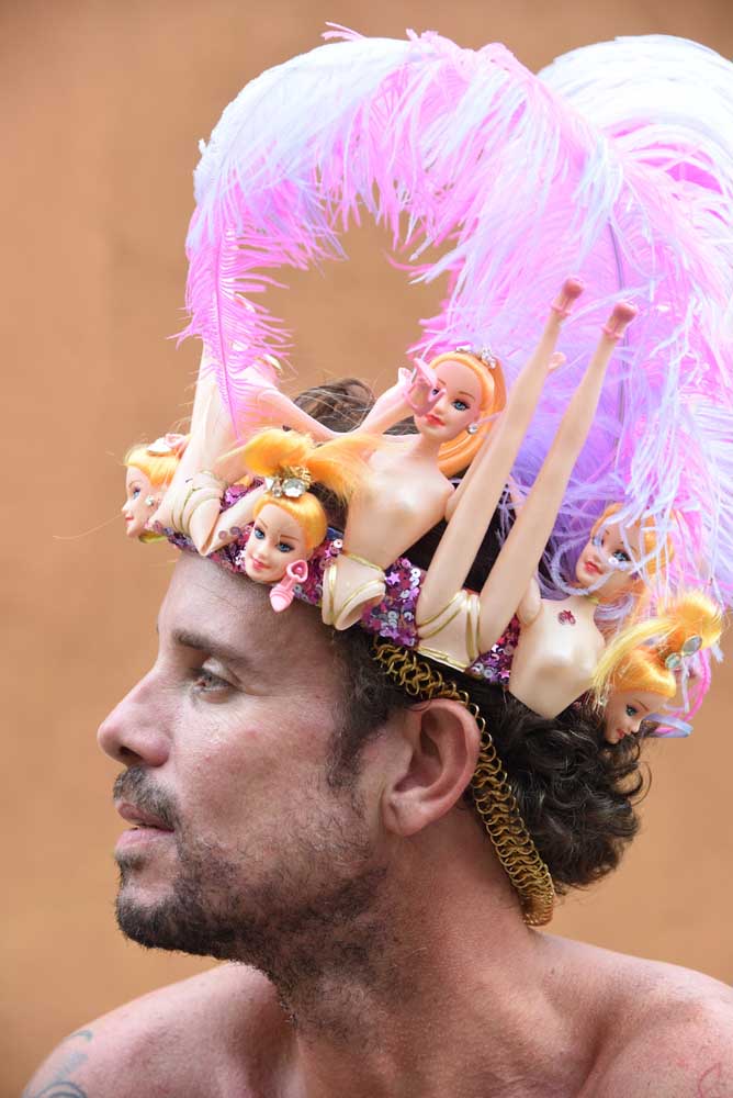 Um adereço de cabeça inusitado e cheio de diversão feito com bonecas de plástico e penas cor de rosa.