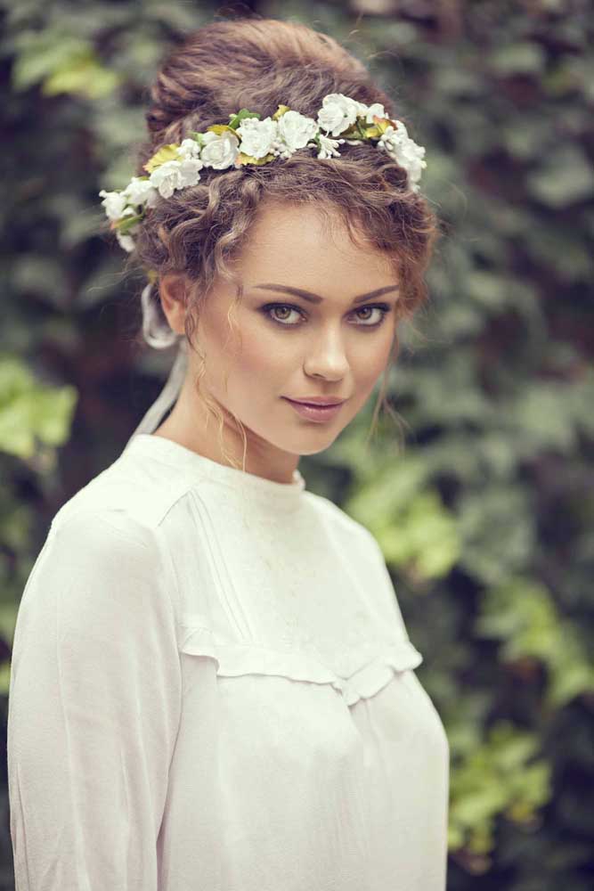 Outra opção de coque em cabelo cacheado para noiva, desta vez com direito a uma tiara de flores. 
