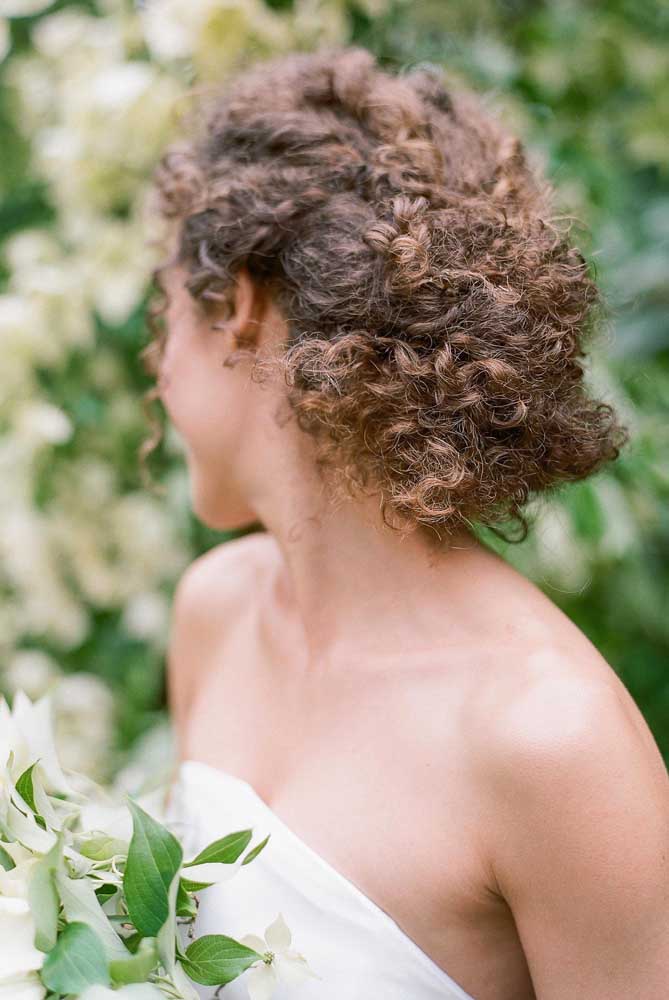 Penteado clássico para noivas, o coque baixo fica incrível em cabelos cacheados - não importa a curvatura!
