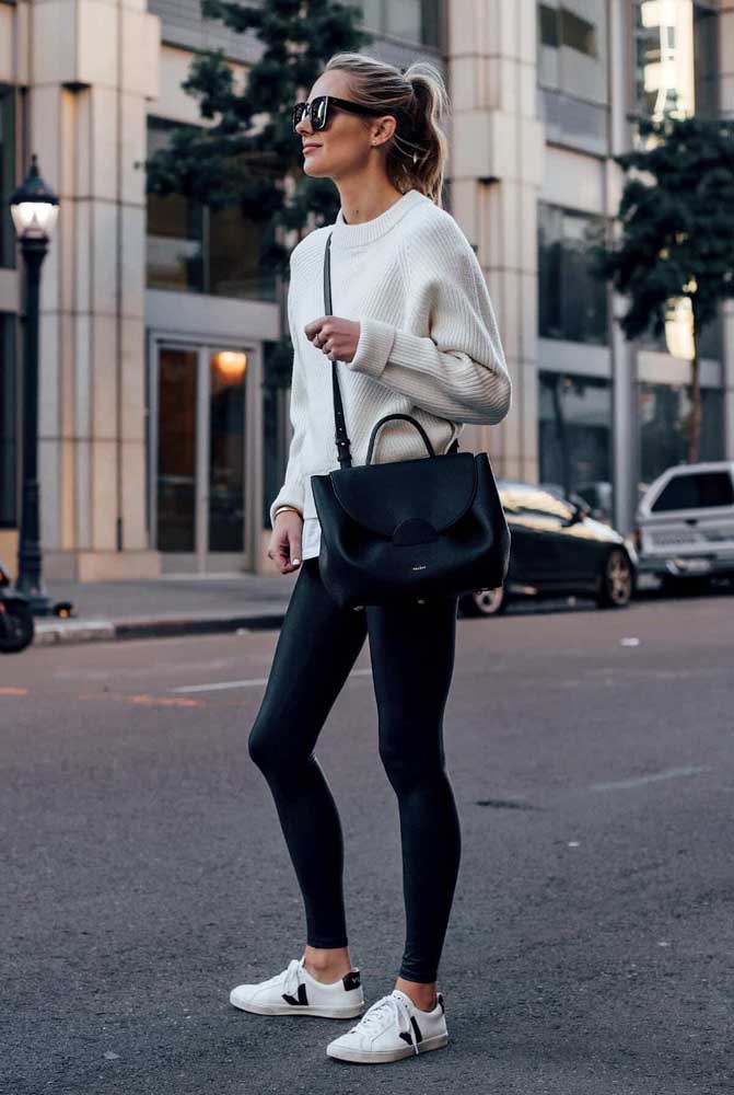 Uma combinação de casaco de tricô e tênis casual brancos com legging preta para os dias de inverno. 
