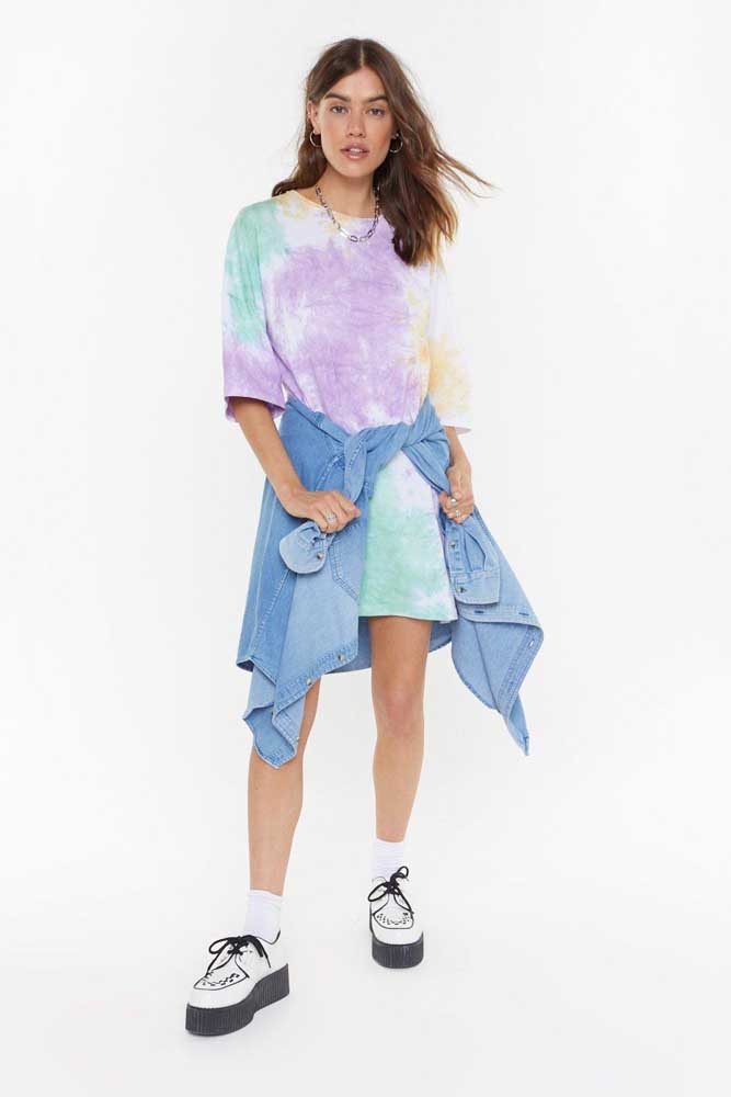 Outra ideia é amarrar uma camisa na cintura, como neste look super nostálgico e jovem com camiseta tie dye usada como vestido, camisa jeans e tênis plataforma.