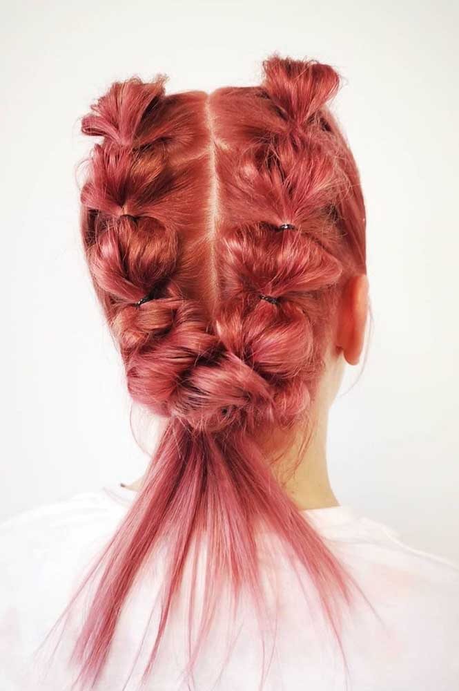 Um penteado divertido no cabelo rosa com duas tranças embutidas faltas feitas com a ajuda de elásticos fininhos. 