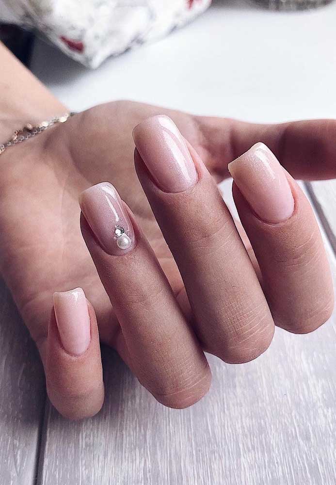 A pérola aplicada sobre a filha única traz ainda mais delicadeza para estas unhas com esmalte rosa clarinho com glitter.