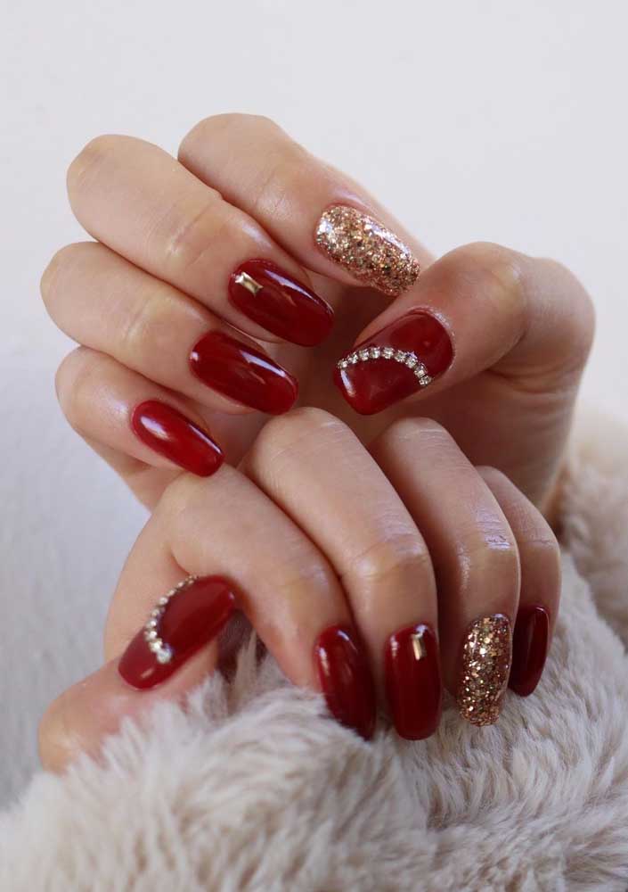 Muita ousadia nesta composição de vermelho e dourado, com destaque para as unhas dos polegares, com aplicação de uma meia lua de strass.
