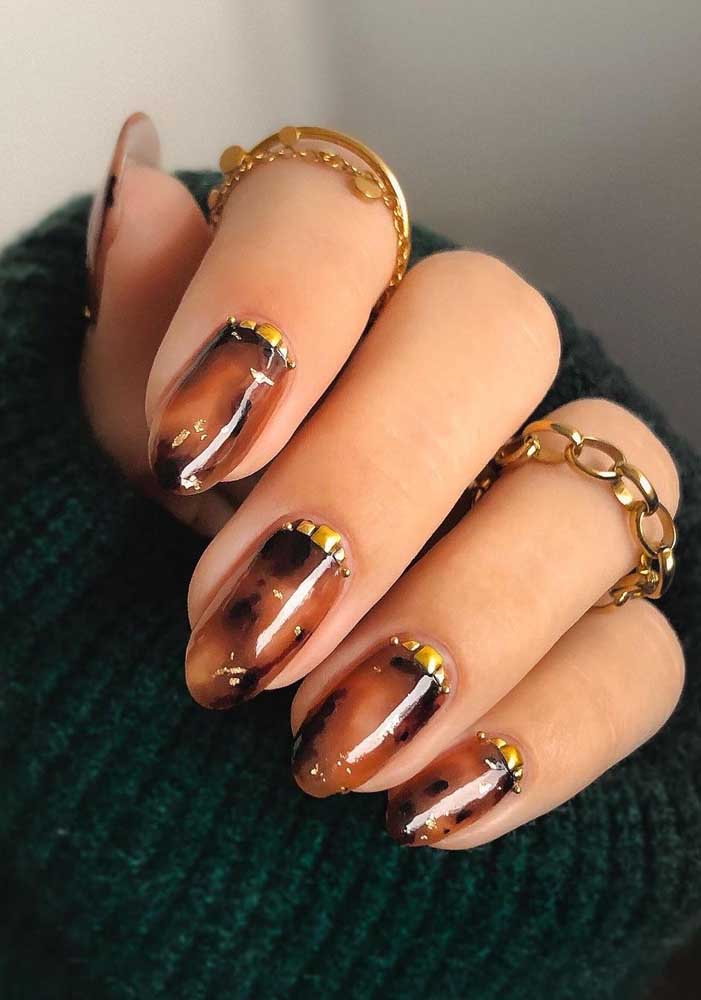 Muito brilho e profundidade nestas unhas marmorizadas, que ganham um toque a mais com jóias amarelas contornando a cutícula. 