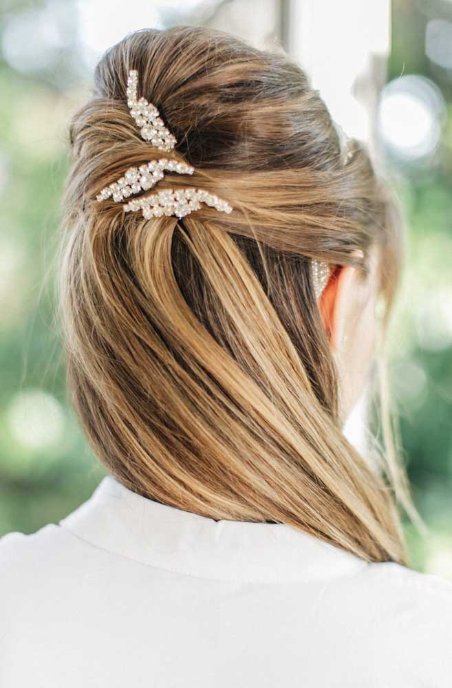 Um exemplo mais tradicional de penteado para casamento que tem uma parte de trás volumosa que contornada com as mechas da frente, que se encontram e formam uma torção antes de caírem soltas junto ao restante do cabelo.