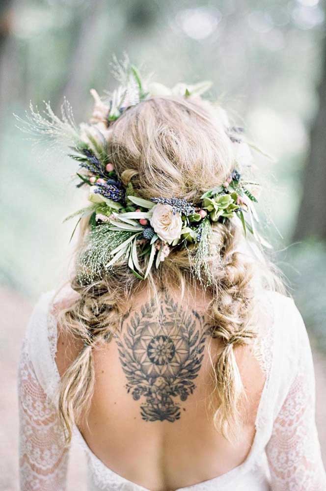 As duas tranças bem soltas e bagunçadinhas com uma coroa de folhas e flores deixam o visual alinhado com a temática boho chic do casamento.