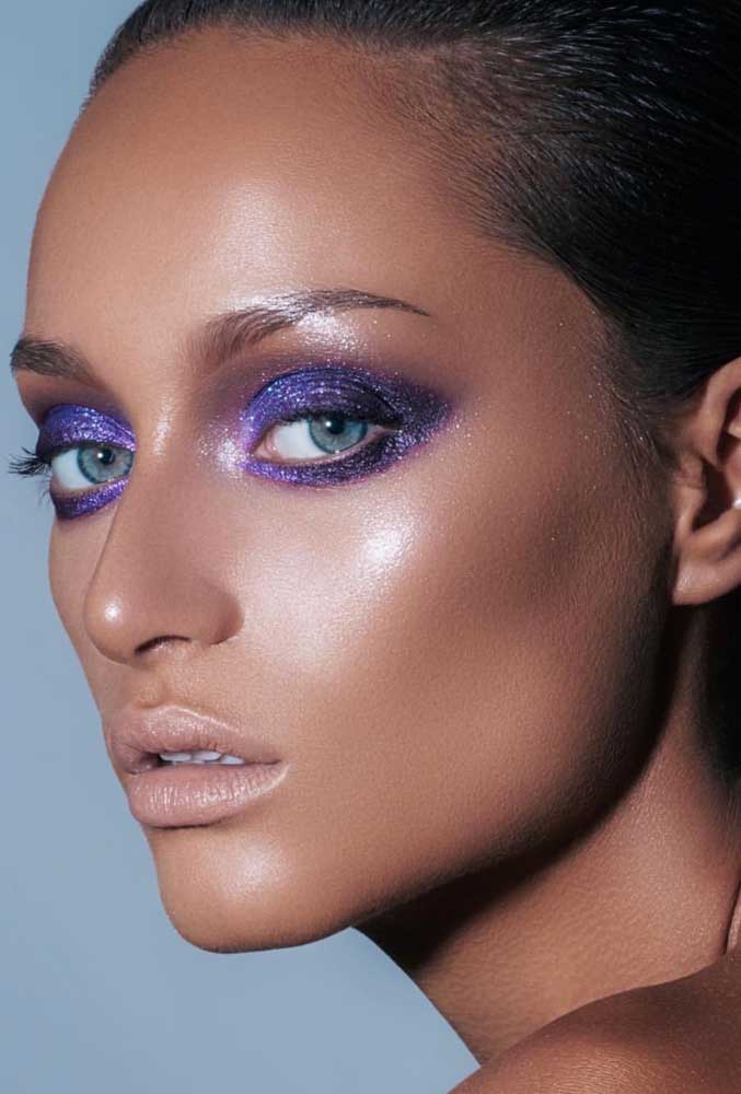 Toda a atenção voltada para a sombra glitter violeta que toma as pálpebras superiores e inferiores nessa make com batom e blush nude com pele em subtom frio.