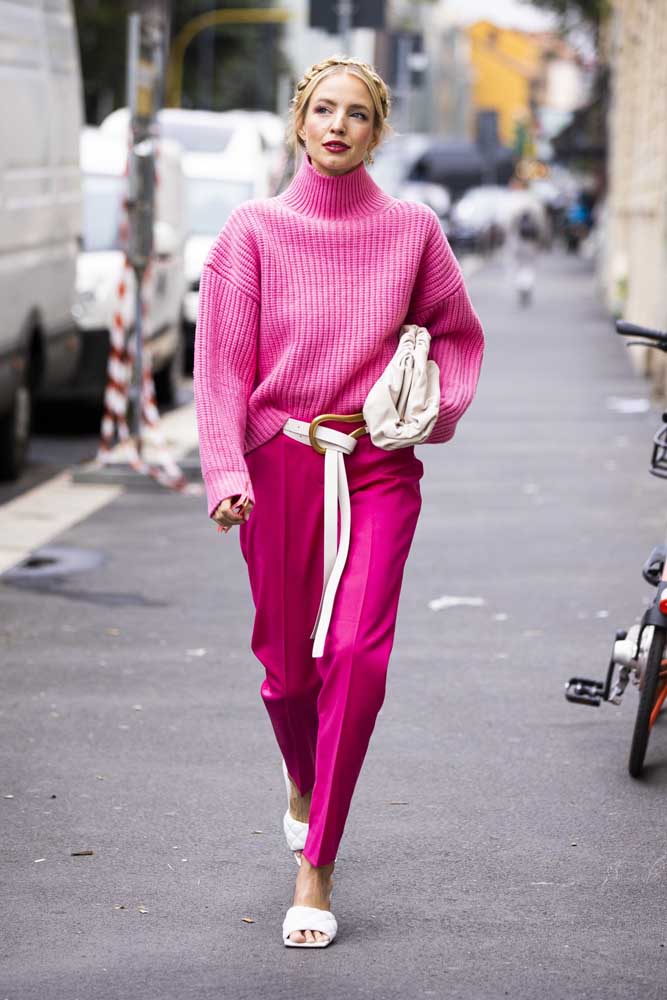 Um look monocromático rosa com suéter de gola alta bem soltinho, calça social, cinto, bolsa e tamanco branco para passear pela cidade no perfeito estilo anos 80.