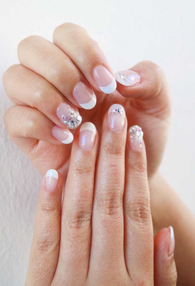 O glitter e a pedraria super brilhante dão um toque de glamour para as unhas clássicas de noiva com francesinha branca.