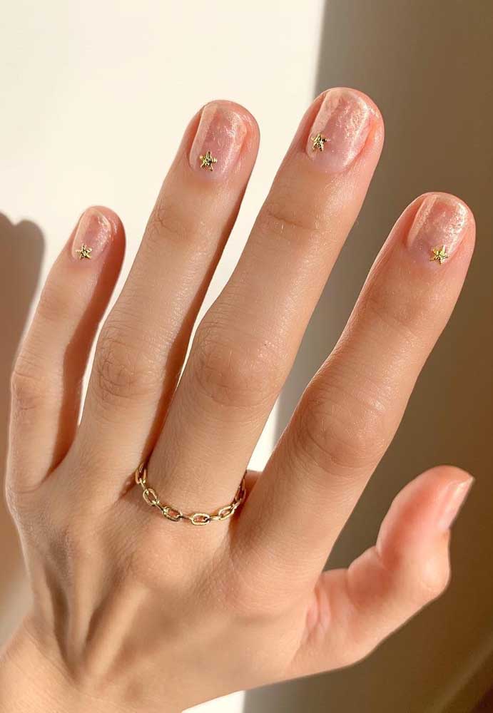 As estrelas douradas aplicadas dão o toque final nessas unhas para casamento pintadas com esmalte perolado transparente.