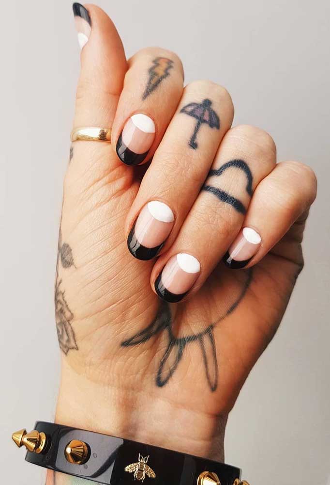 União de três tendências da nail art 2022 em uma composição só: a francesinha angular em preto, a meia lua em branco e a área central no tom natural da unha. 