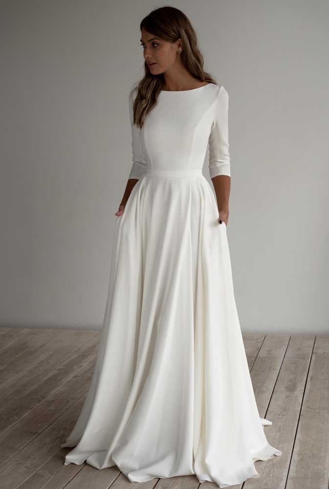 Começando com um vestido de noiva simples e elegante: num modelo evasê com saia longuíssima e, na parte de cima, um decote canoa e manga média. 