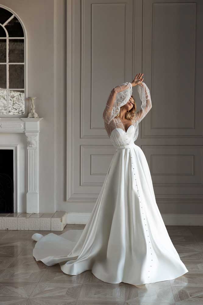 Retrô sem perder sua modernidade: vestido de noiva evasê sem mangas, mas com uma sobreposição de manga longa transparente.