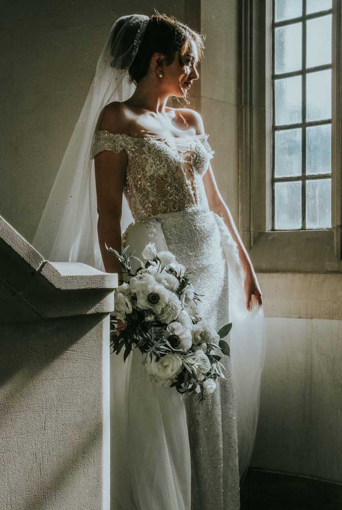 A camada de tule também traz um pouco de volume para este vestido de noiva com corte reto, combinando com o véu da grinalda. 