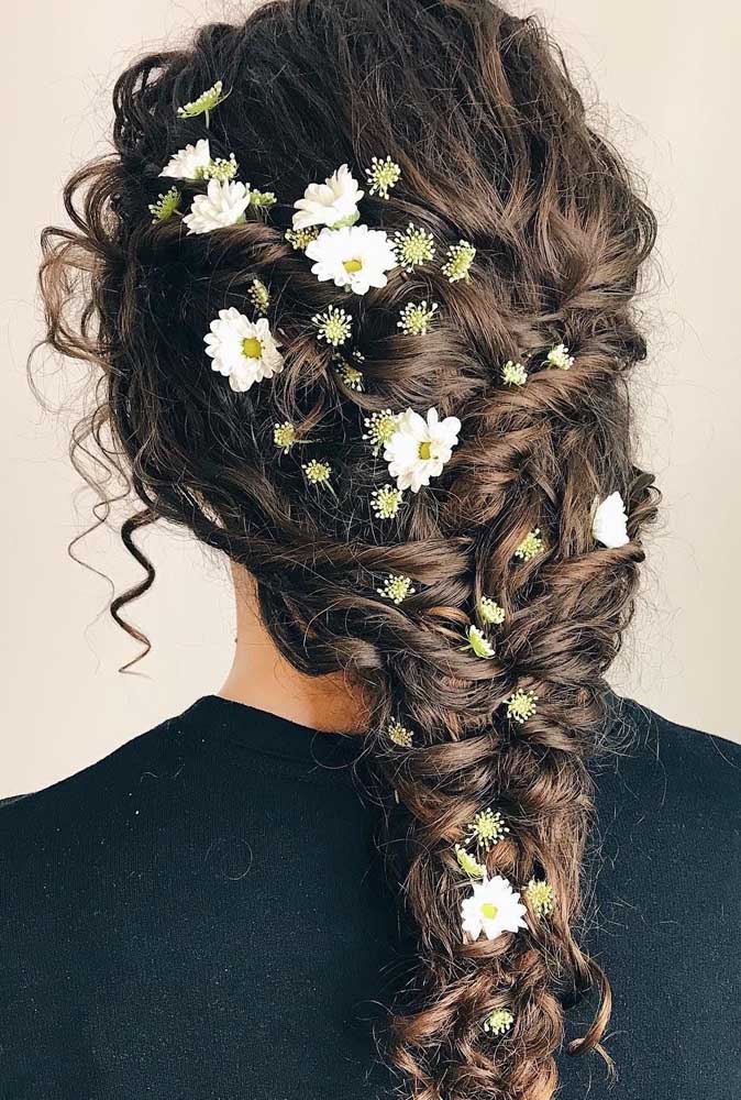 No melhor estilo cottagecore, um penteado para cabelo cacheado com trança simples totalmente adornado com margaridas.