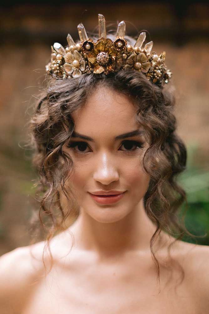 A franja solta dividida ao meio e a coroa de flores e pedras trazem mais volume para esse penteado preso. 