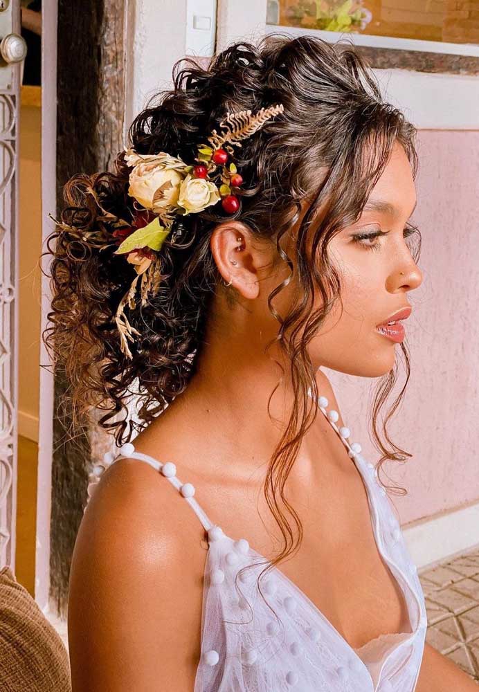 Inspire-se nesse penteado de cabelo cacheado para casamento preso mas, ao mesmo tempo, bem soltinho e leve, adornado com um arranjo de flores secas.