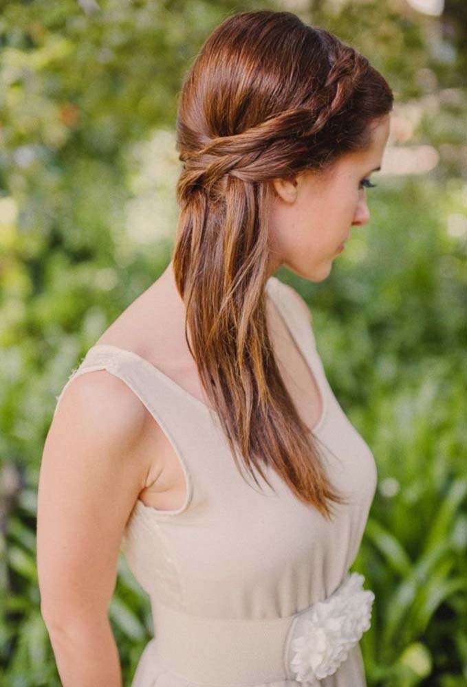 As tranças feitas com as mechas laterais contornam a cabeça formando uma tiara enquanto o restante do cabelo permanece solto, colocado de lado.