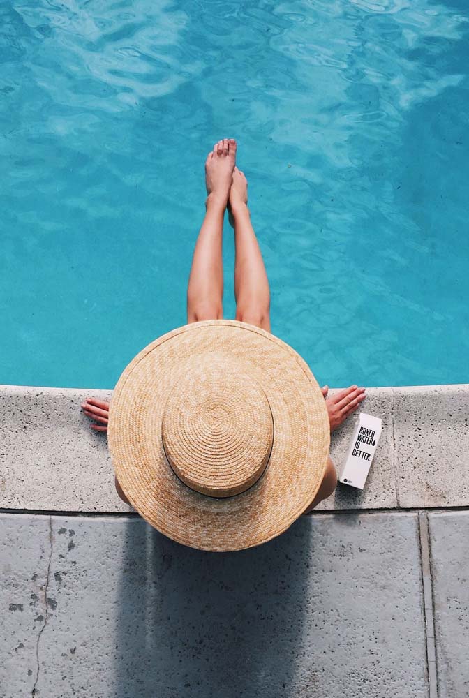 A foto tumblr na piscina clássica: vista de cima, com um chapéu de aba bem larga cobrindo a maior parte do corpo e a água bem azul.
