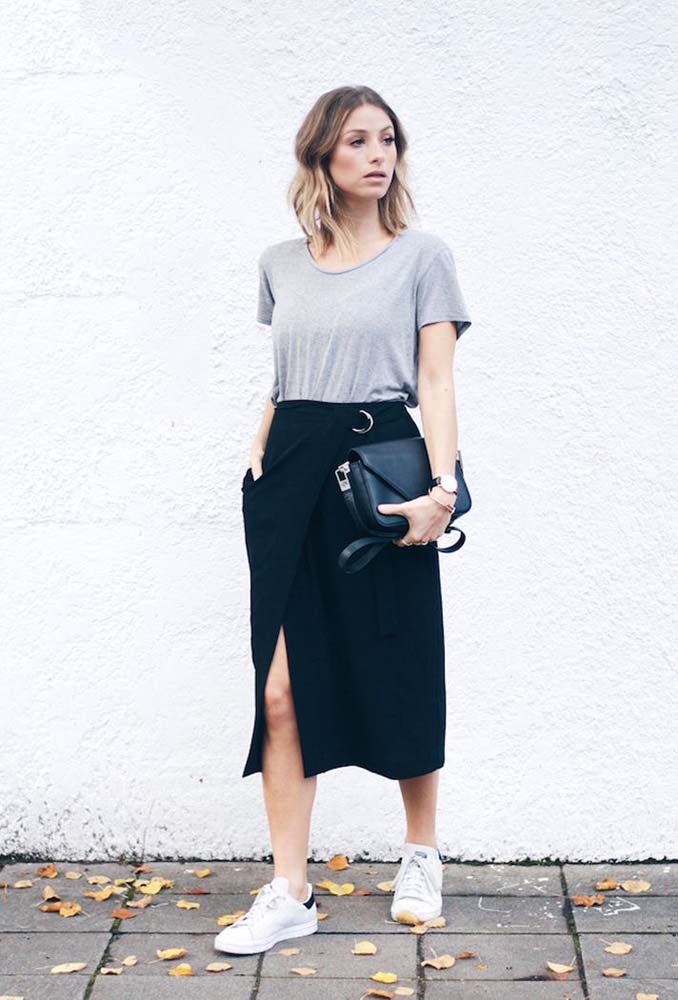 Um look com saia preta mini envelope com camiseta cinza e tênis casual, o visual confortável e despojado para o trabalho ou para curtir o dia de lazer.
