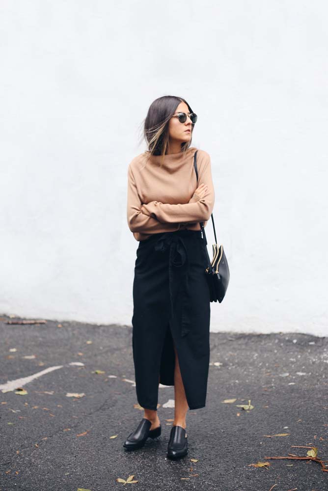 A saia preta envelope também está presente neste look sóbrio para os dias frios, com uma blusa bege de manga longa e sapato mule. 
