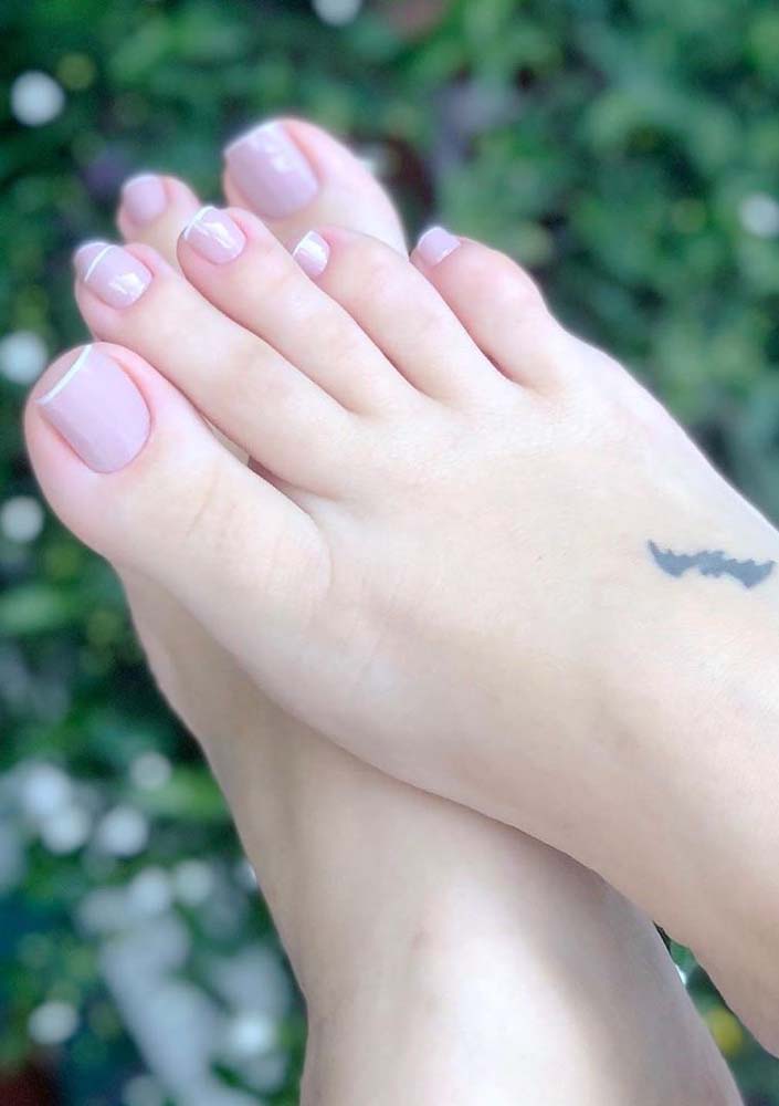 Simplicidade e elegância nas unhas do pé decoradas com francesinha branca no fundo clarinho. 