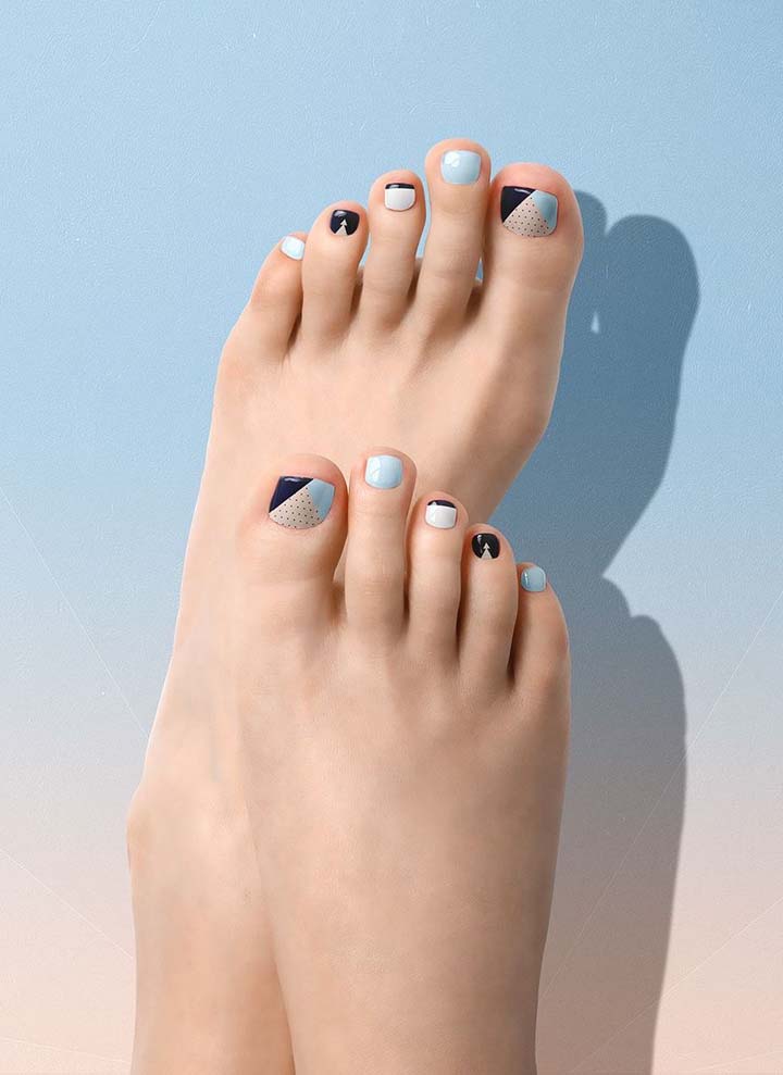 O geométrico domina essas unhas do pé decoradas com diferentes motivos em tons de azul, branco e bege.