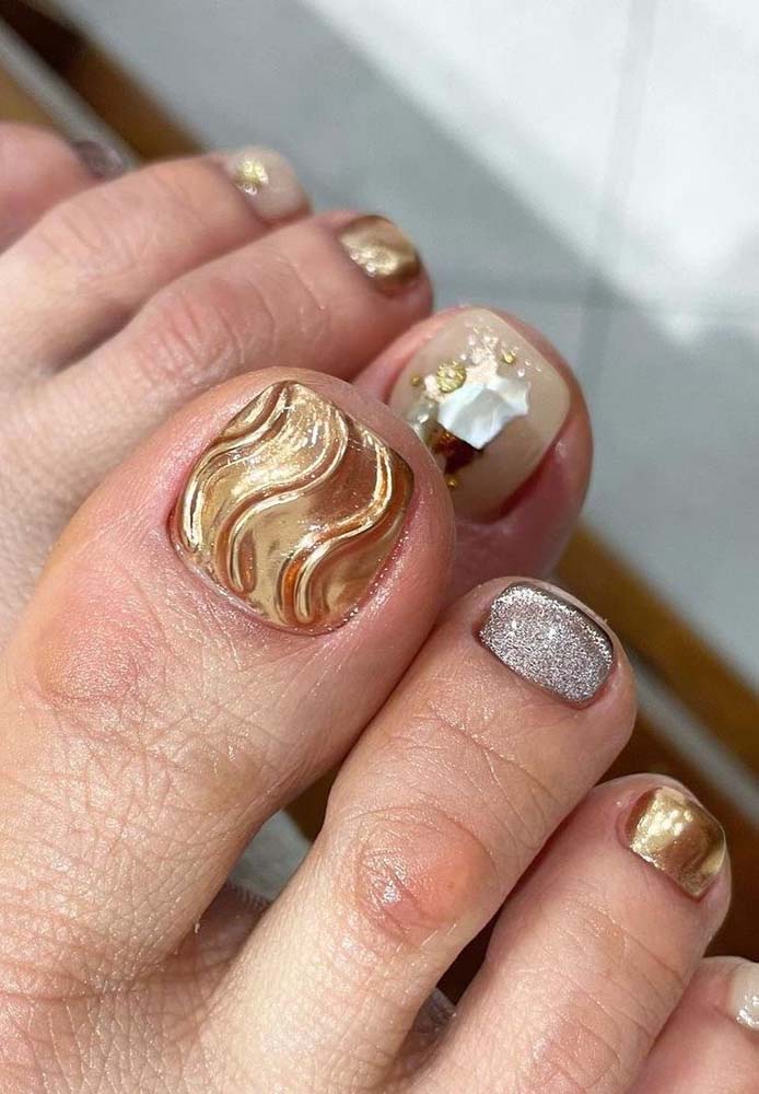 Outra inspiração de unhas do pé decoradas bem festivas, ótimas para usar no ano novo, com aplicação de pedras, esmalte dourado metalizado e com glitter prateado.