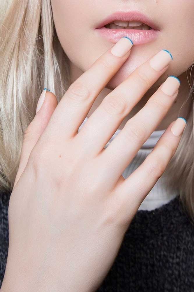 Uma nail art muito sutil nesta linha fininha de azul nas pontinhas das unhas retas nude.