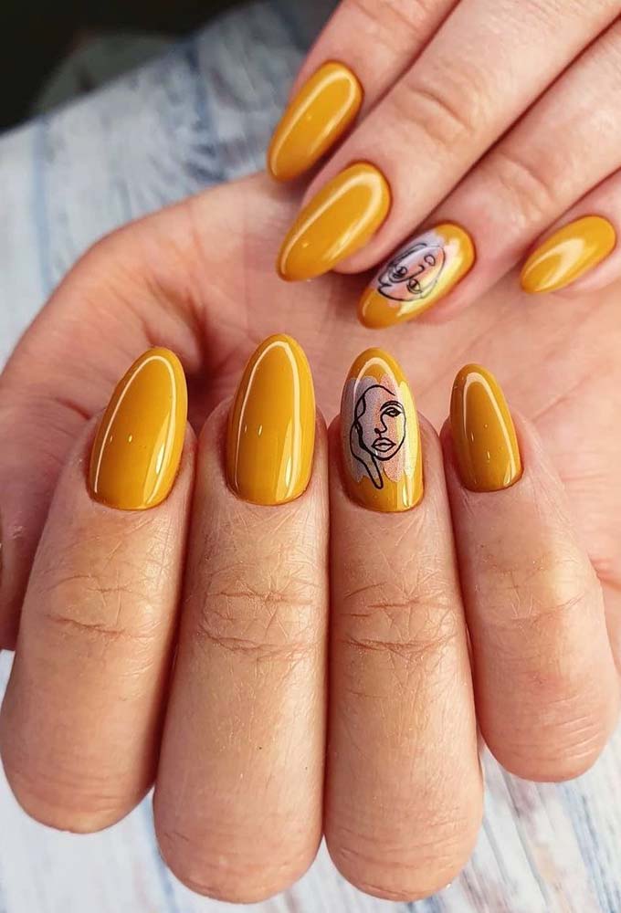 O amarelo mostarda, um dos tons mais queridinhos do estilo tumblr, é o protagonista dessa unha stiletto com um desenho de rosto estilizado na filha única. 