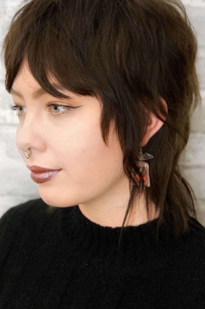 Em primeiro lugar, um visual bem despojado e retrô, queridinho da GenZ: o wolf cut curto com franja cortina desfiada.