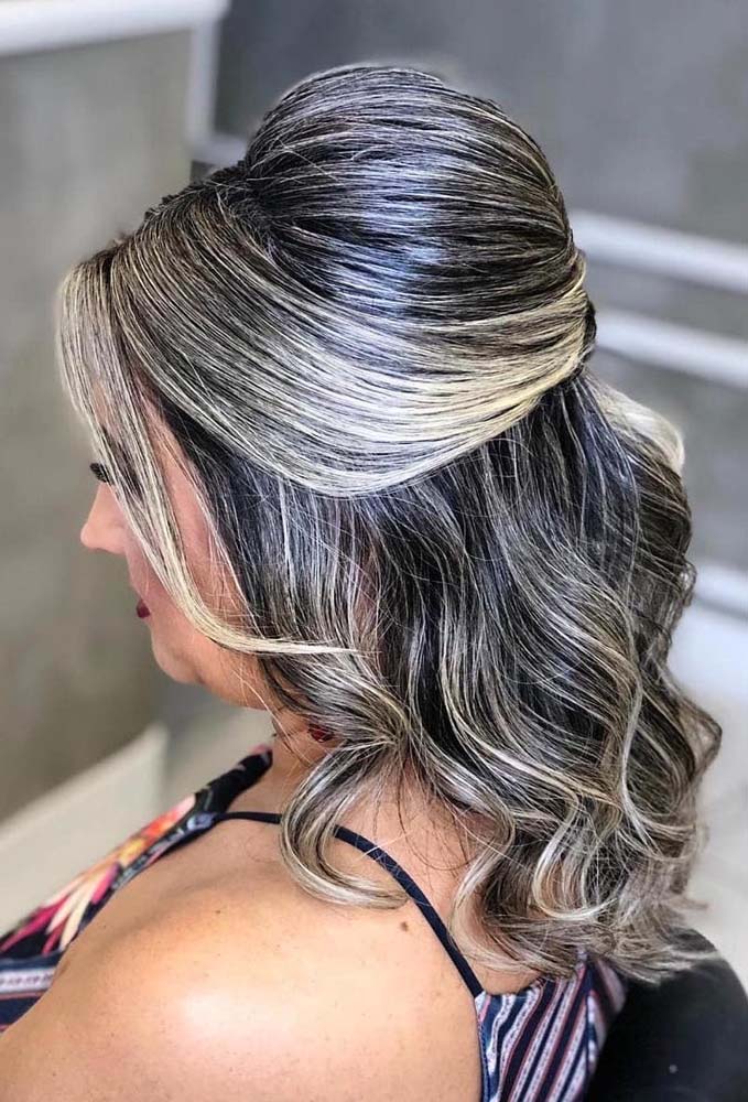 Penteado com cabelo médio para madrinha com bastante volume no topo da cabeça, duas mechas da franja longa soltas e o restante dos fios finalizados com cachos bem abertos. 